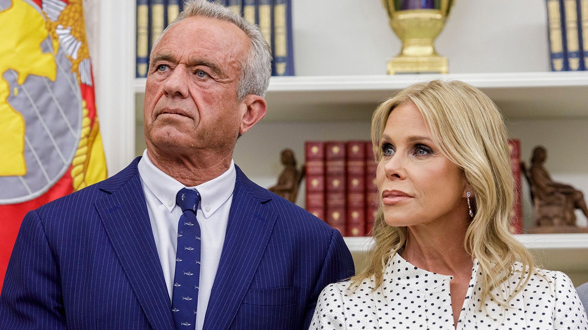 Robert F. Kennedy Jr. stands beside his wife, actress Cheryl Hines, during a ceremony in the Oval Office.