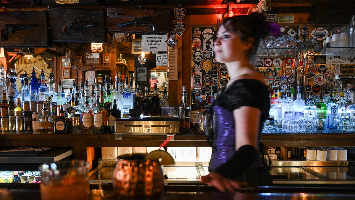 O barman caminha atrás do bar do Saloon No. 10 em Deadwood, Dakota do Sul. Garrafas, decorações e coquetéis são vistos por aí.