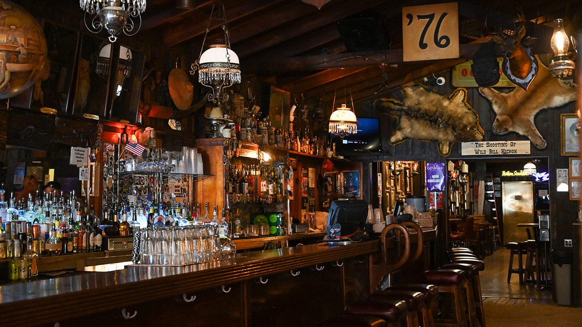 Historic Saloon No. 10 bar in Deadwood, South Dakota, seen with barstools lined up, hanging lamps and decor.