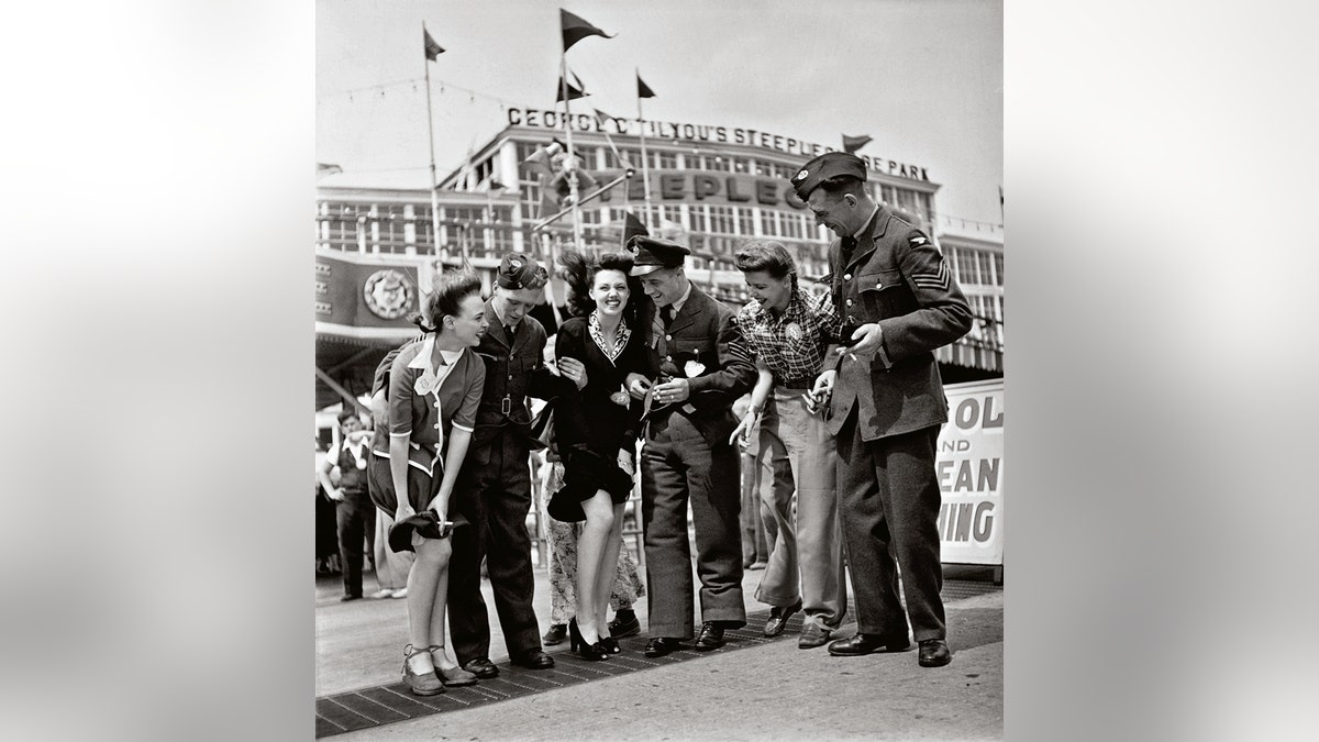 Soldiers helping a woman hold on to her flying skirt.
