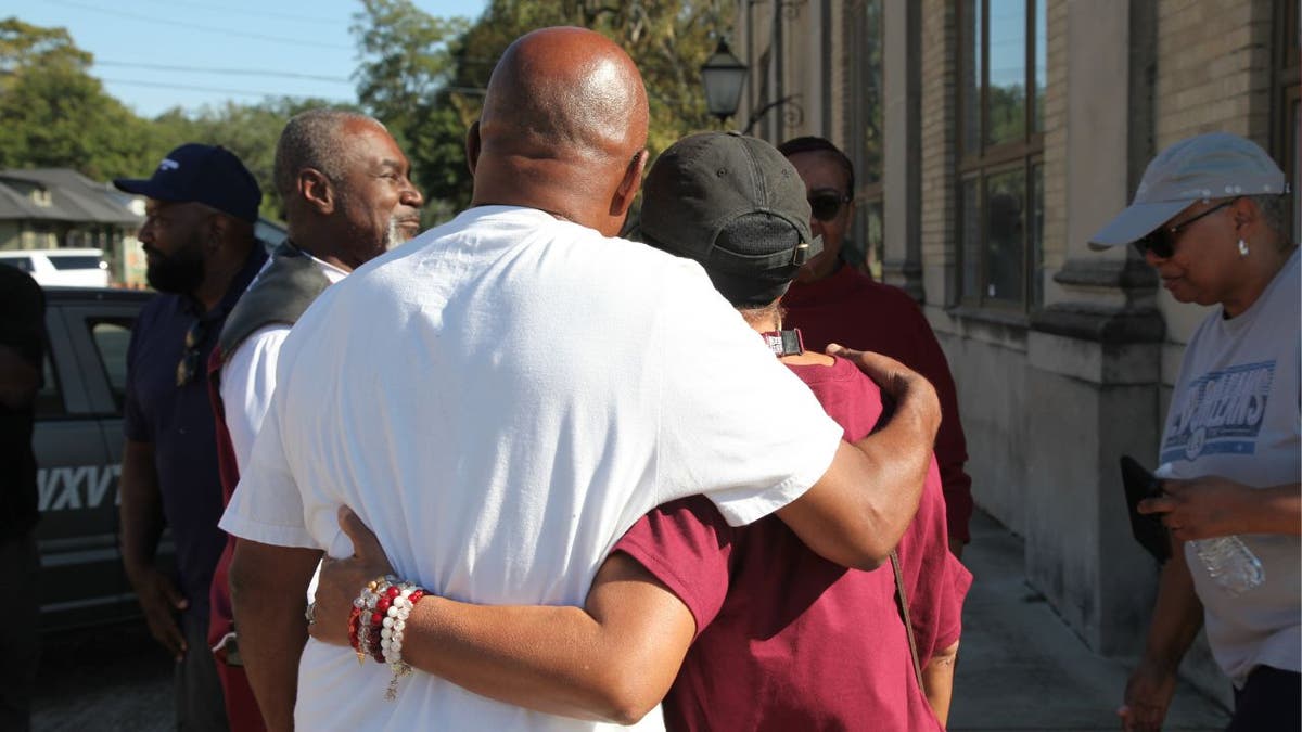 People hug outside Leland City Hall after a deadly mass shooting in Mississippi.