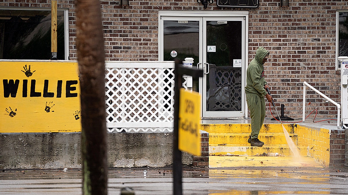 Man cleaning blood of steps at Willies Bar in South Carolina.