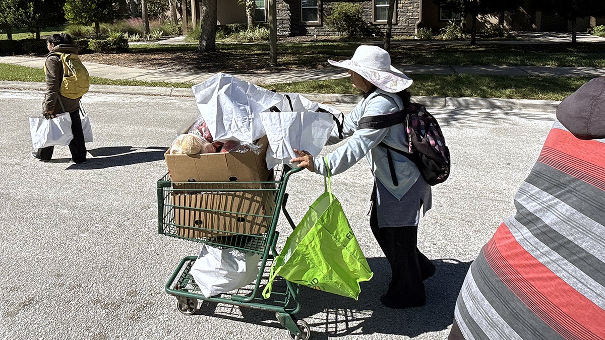 Mujer con carrito de compras en Florida busca ayuda de un banco de alimentos