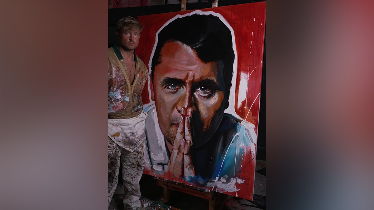 Sam Ryan standing next to his portrait of Charlie Kirk.
