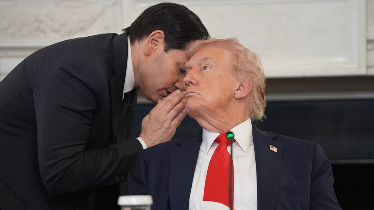 El secretario de Estado, Marco Rubio, le susurra al presidente Donald Trump, quien sostiene la nota que Rubio le entregó, durante una mesa redonda sobre Antifa en el Comedor Estatal de la Casa Blanca, el miércoles 8 de octubre de 2025, en Washington. (Foto AP/Evan Vucci)