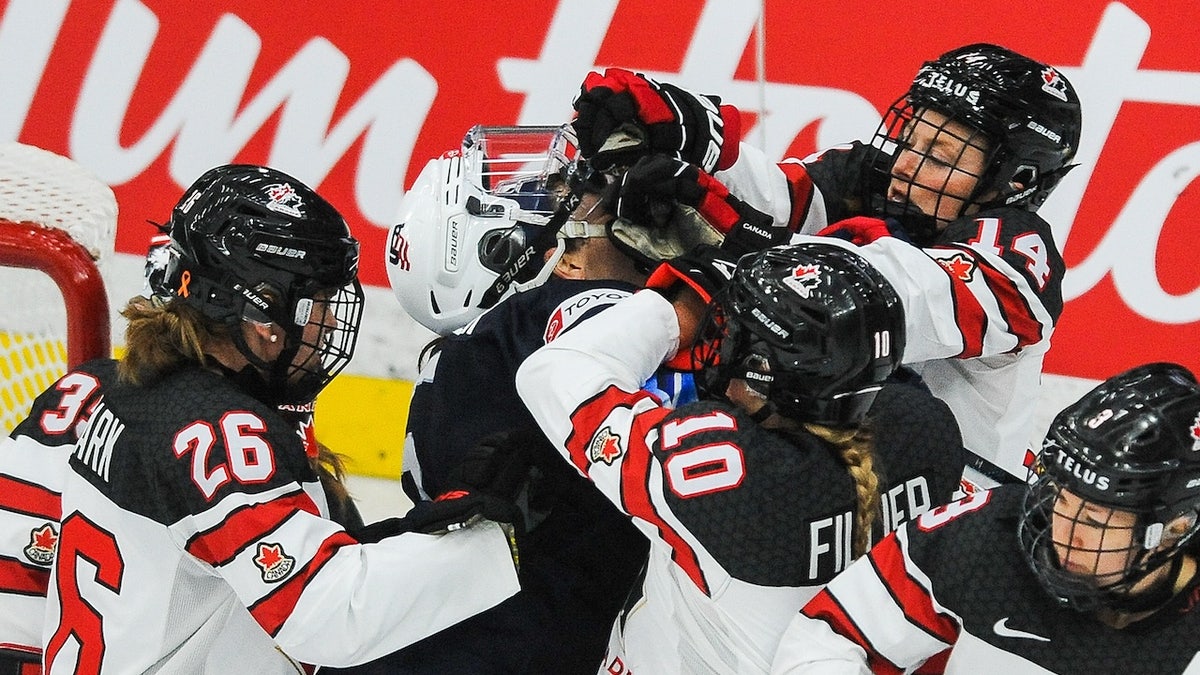 Emily Clark #26, Sarah Fillier #10, and Renata Fast #14 of Canada fight Megan Keller #5 of United States in the 2021 IIHF Women's World Championship Group A match played at WinSport Arena on August 26, 2021 in Calgary, Canada.
