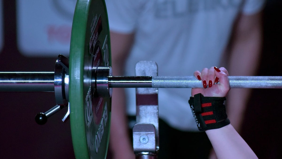 A female powerlifter gripping a barbell during competition.
