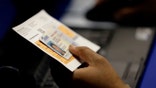 election official checks a voter's photo identification