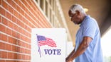 Elderly man votes at booth.