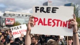 protestors hold up free palestine posters at demonstration in Warsaw.