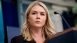 White House Press Secretary Karoline Leavitt stands behind the microphone at the podium in the press briefing room