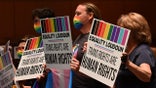 Parents hold signs favoring a rule offering protections for transgender students