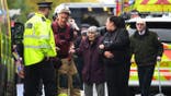 Rescuers and police escort elderly woman and others after synagogue terror attack in Manchester.