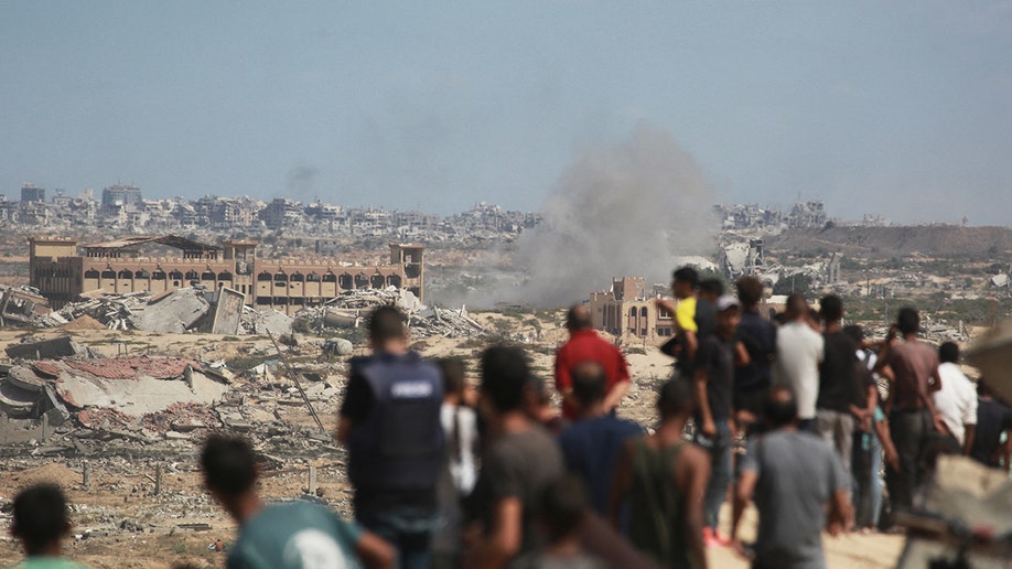 Palestinians watch smoke billowing during Israeli strikes
