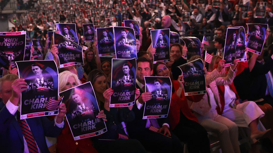Attendees hold Charlie Kirk memorial posters