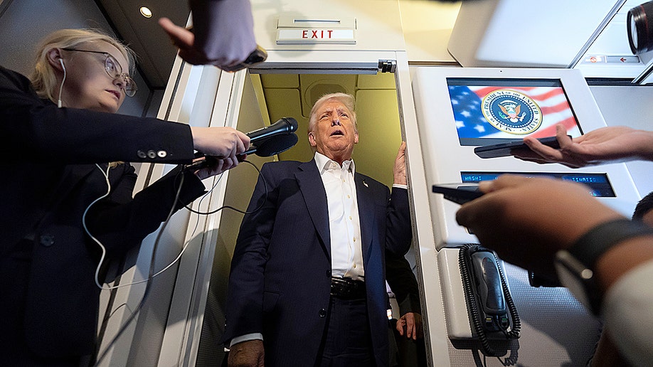 President Donald Trump talking to reporters on Air Force One on his way to Japan