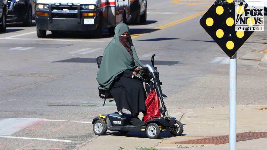 Woman wearing green hijab rides mobility scooter in Cedar–Riverside Minneapolis