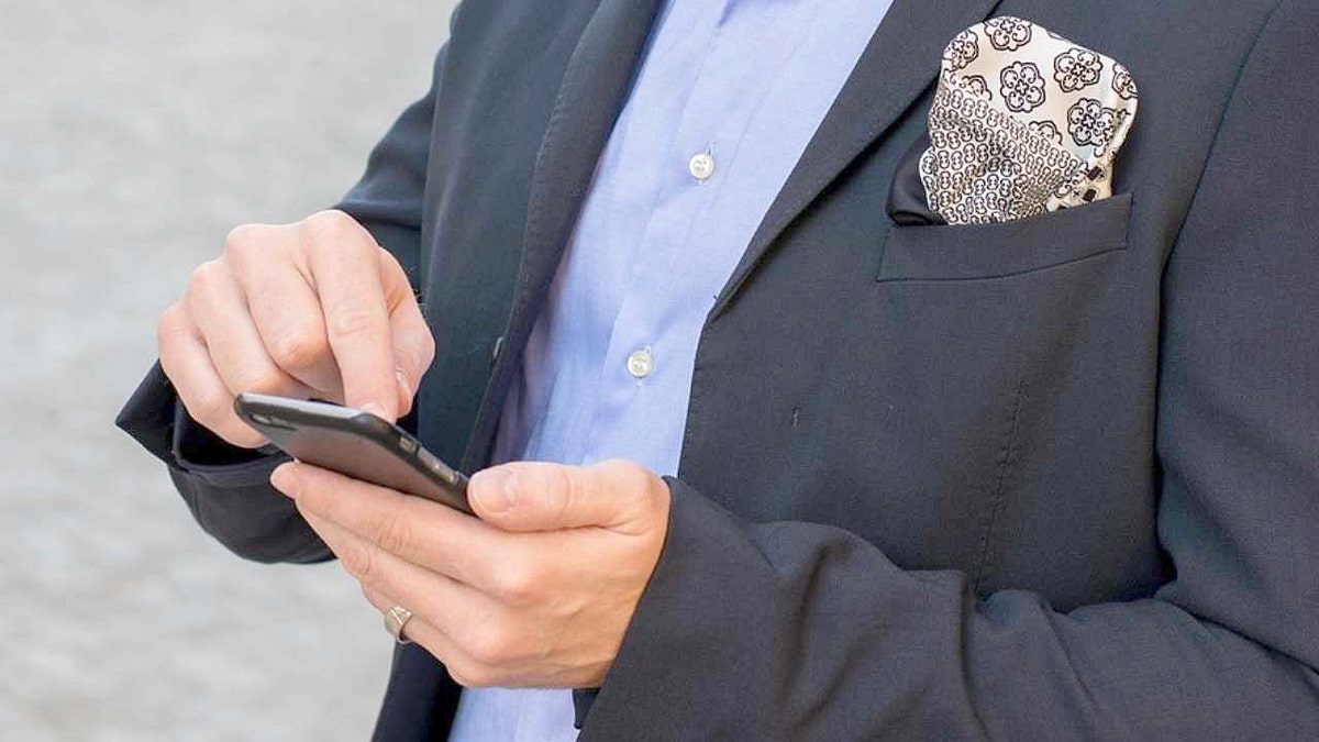 Vīrietis pieskaras viedtālruņa ekrānam.