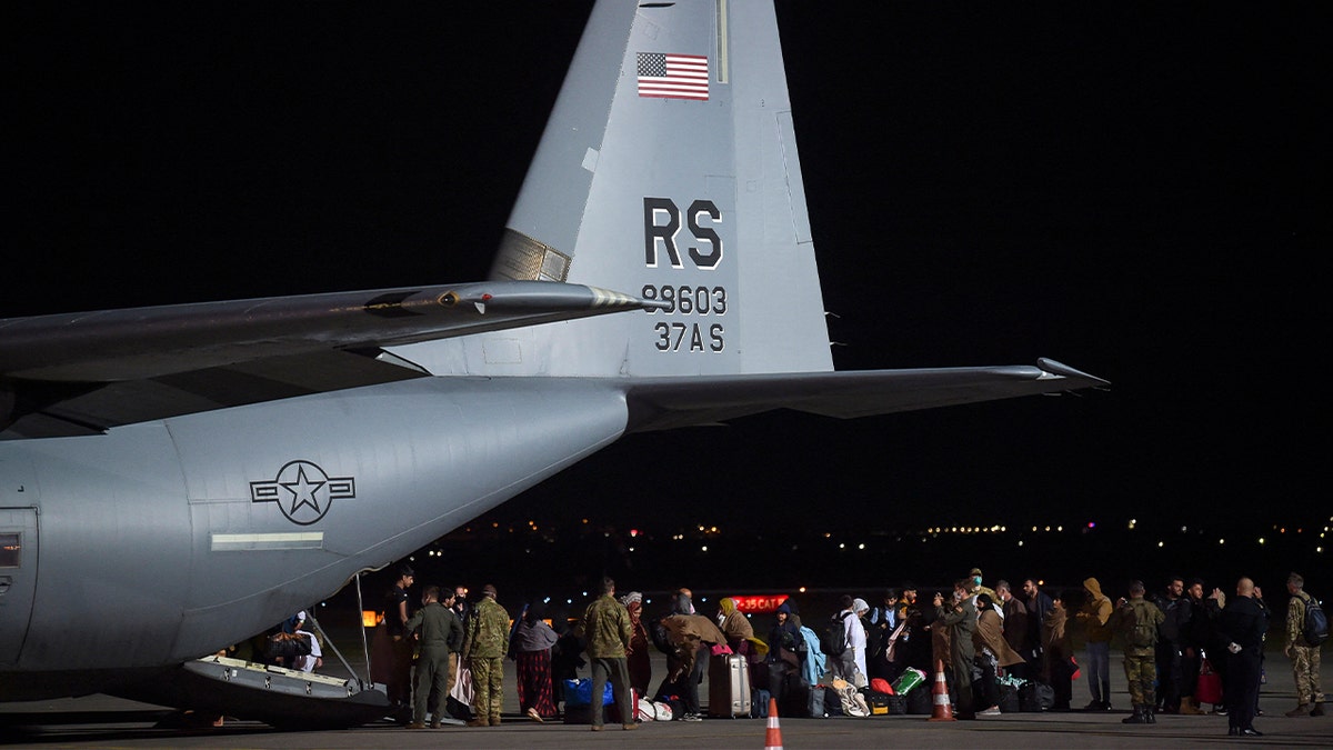 refugees exiting military plane at night