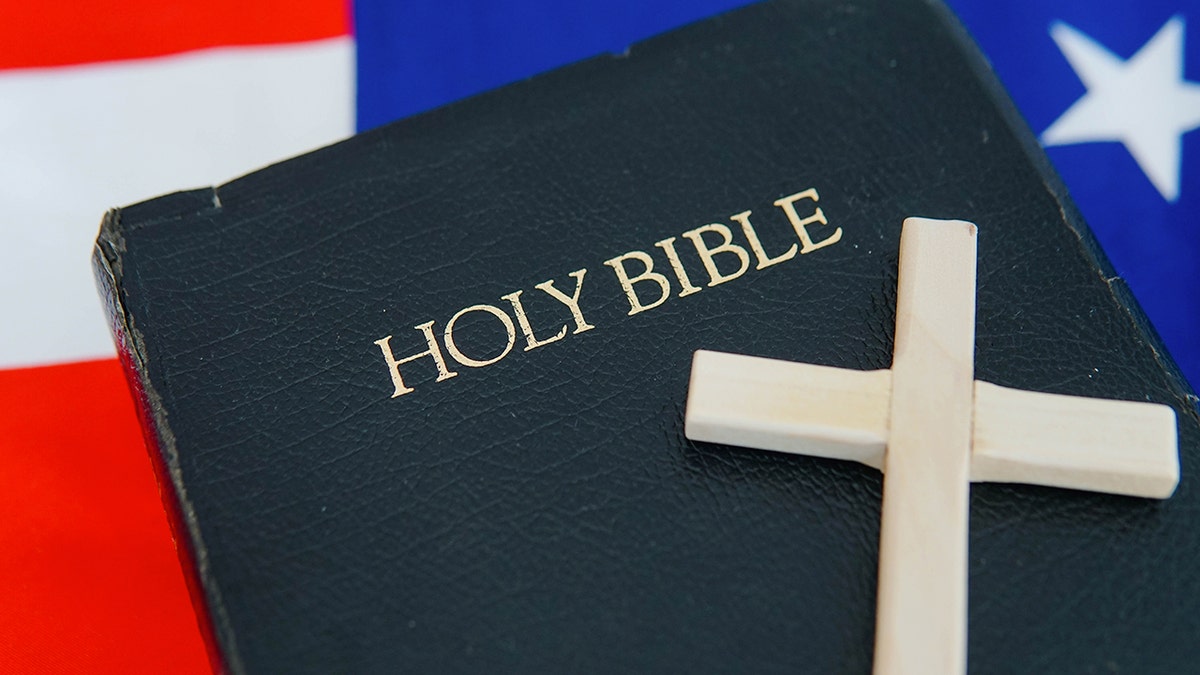 Old Holy Bible with a cross on an American flag