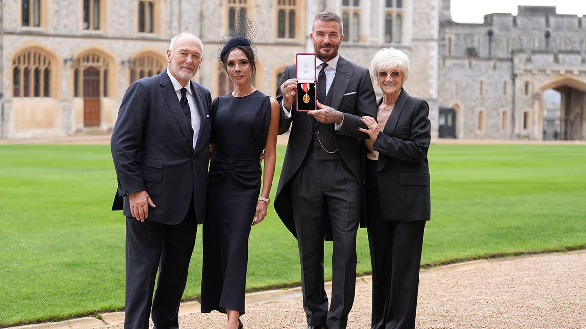 Sir David Beckham poses with his wife Lady Victoria Beckham and his parents Ted and Sandra Beckham outside Windsor Castle after receiving his knighthood.