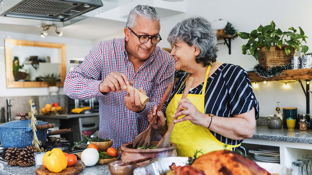 Older couple smiling while preparing Thanksgiving dinner