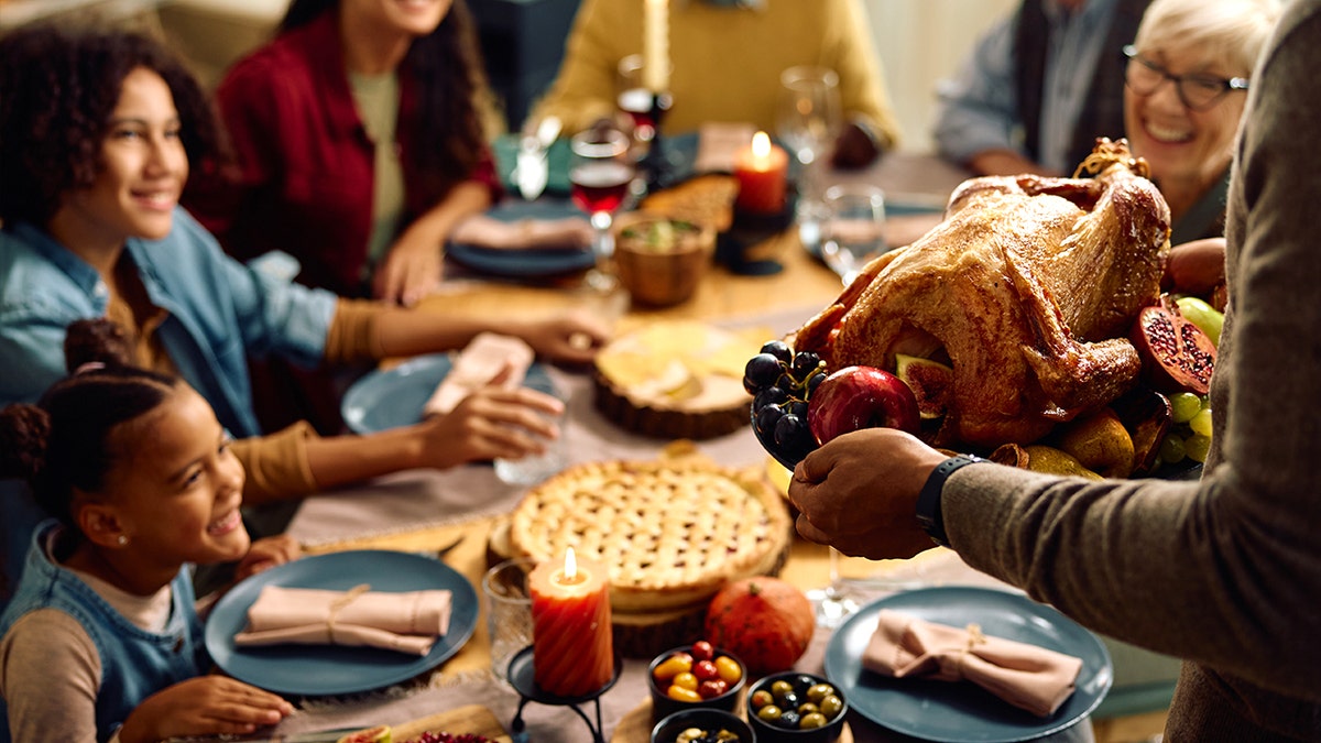 Father bringing turkey to Thanksgiving table