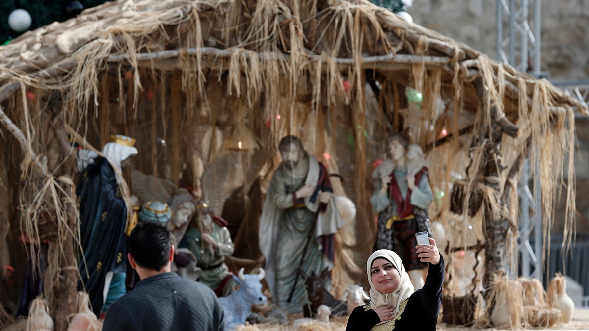 A moslem pistillate takes a selfie representation successful beforehand of a Christian manger connected December 16, 2015 successful the West Bank metropolis of Bethlehem connected the Manger Square adjacent the Church of the Nativity,