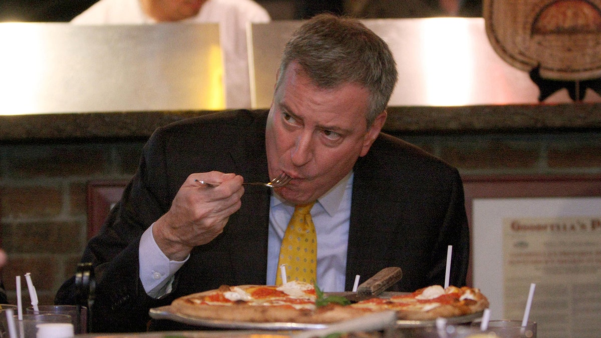 New York City Mayor Bill de Blazio eating pizza with a fork in 2014.
