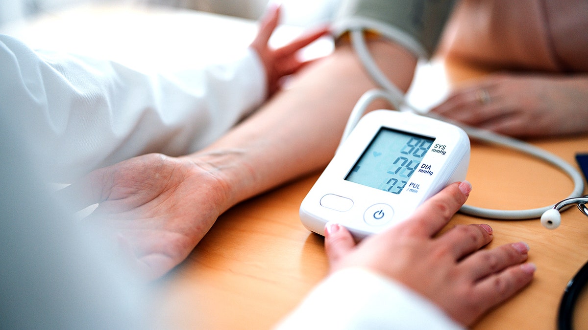 Medical professional measuring blood pressure utilizing a digital monitor during a patient consultation