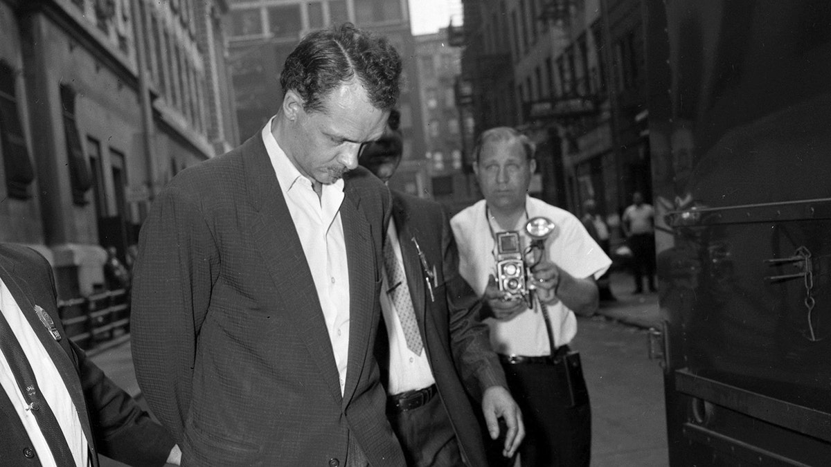 A black and white photo of Charles Terry in custody as he's being photographed.