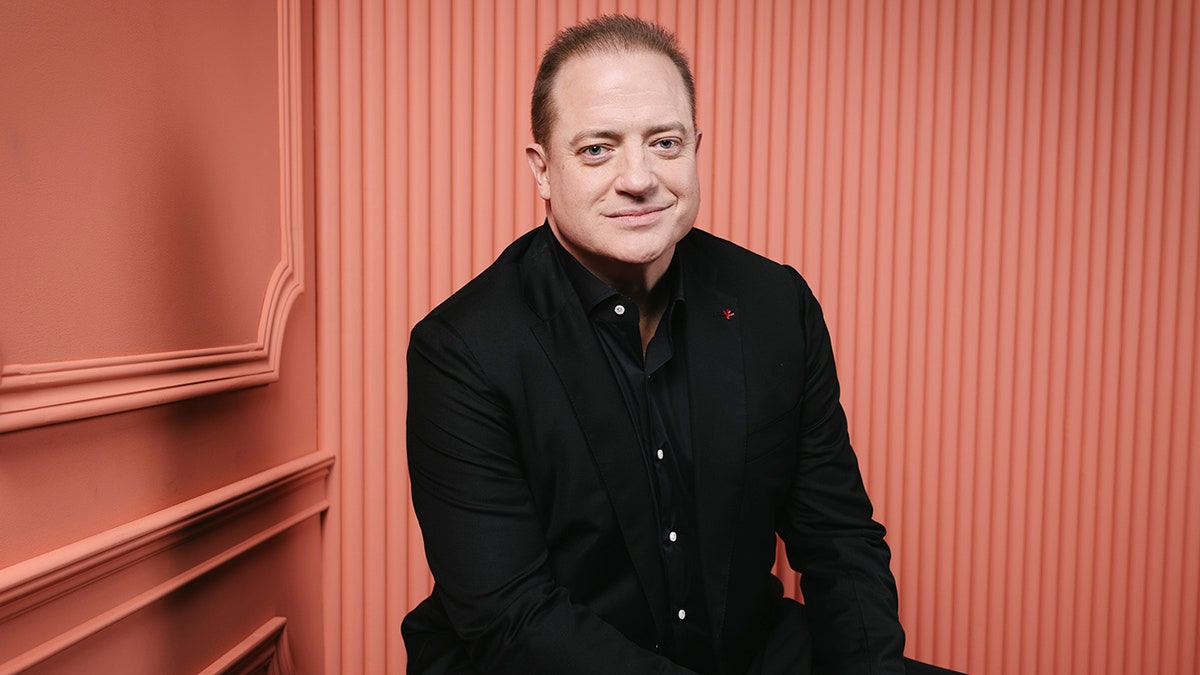 Brendan Fraser poses for a portrait at the 28th SCAD Savannah Film Festival, smiling in front of a neutral backdrop