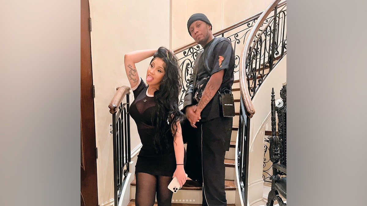 Cardi B stands on a staircase posing for a photo in a black outfit on Thanksgiving 2022, alongside a friend, in an image he shared on Instagram.