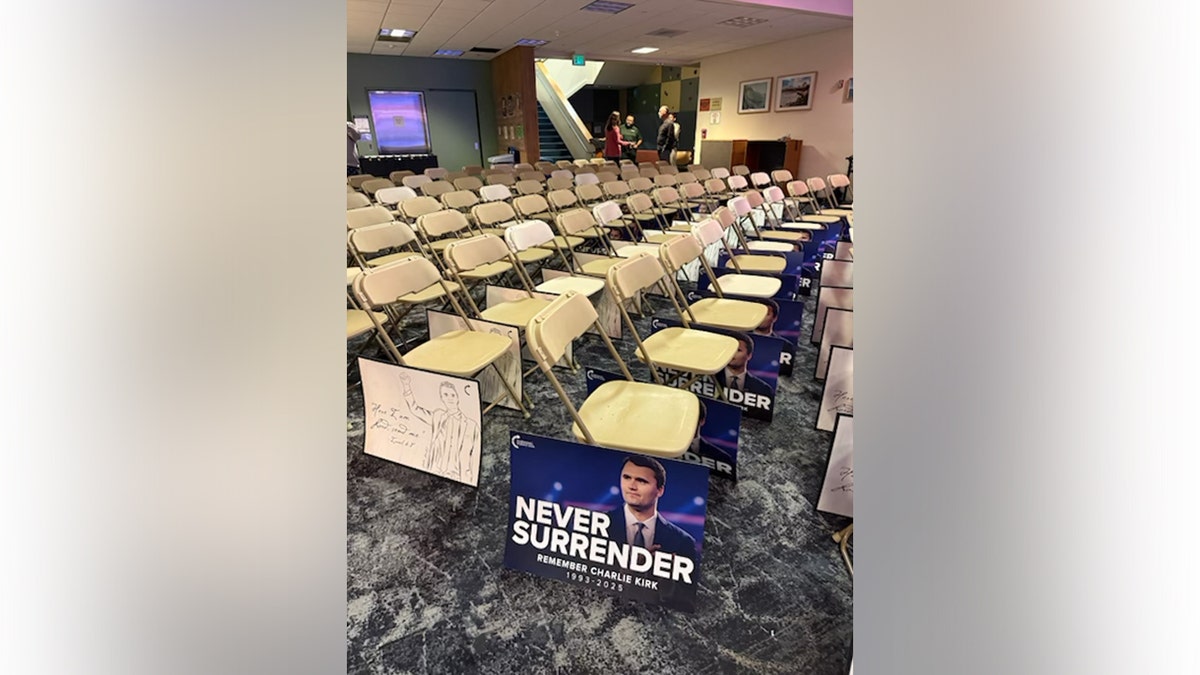 Cadeiras forradas com pôsteres de Charlie Kirk em um memorial.