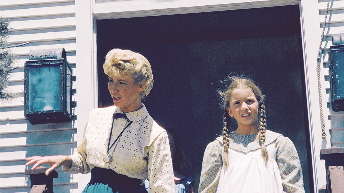 Charlotte Stewart as Miss Beadle standing with a young Melissa Gilbert in costume.