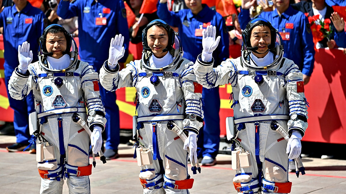 Astronauts for China's Shenzhou-20 mission stand and wave in space suits before mission launch