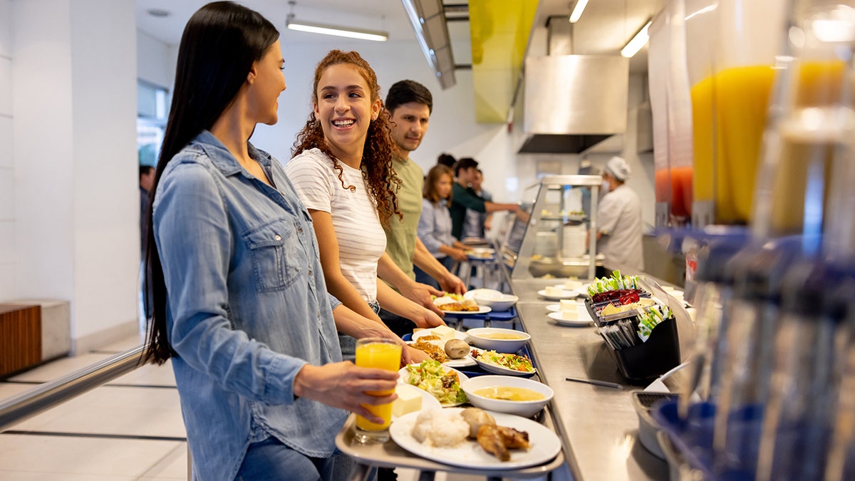 College-aged women talking and smiling in a buffet-style cafeteria