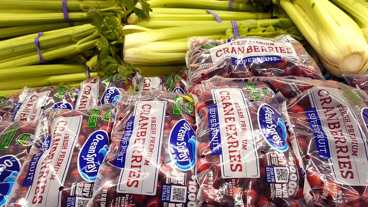 Bags of fresh cranberries and bunches of celery in display at grocery store ahead of Thanksgiving.