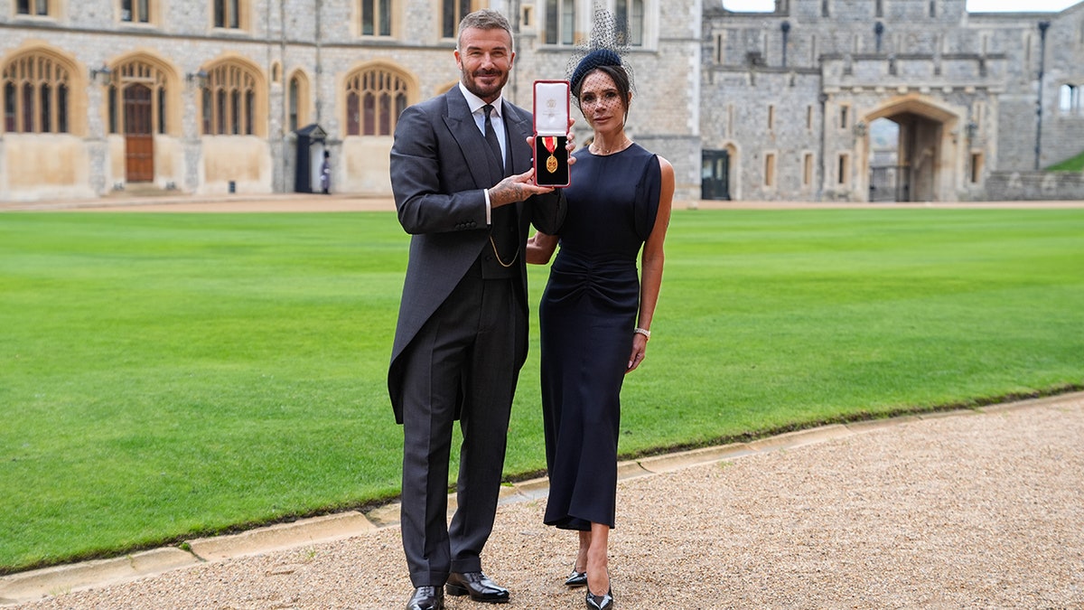 Sir David Beckham and his wife Victoria Beckham pose together after he was knighted at Windsor Castle in Windsor, England.