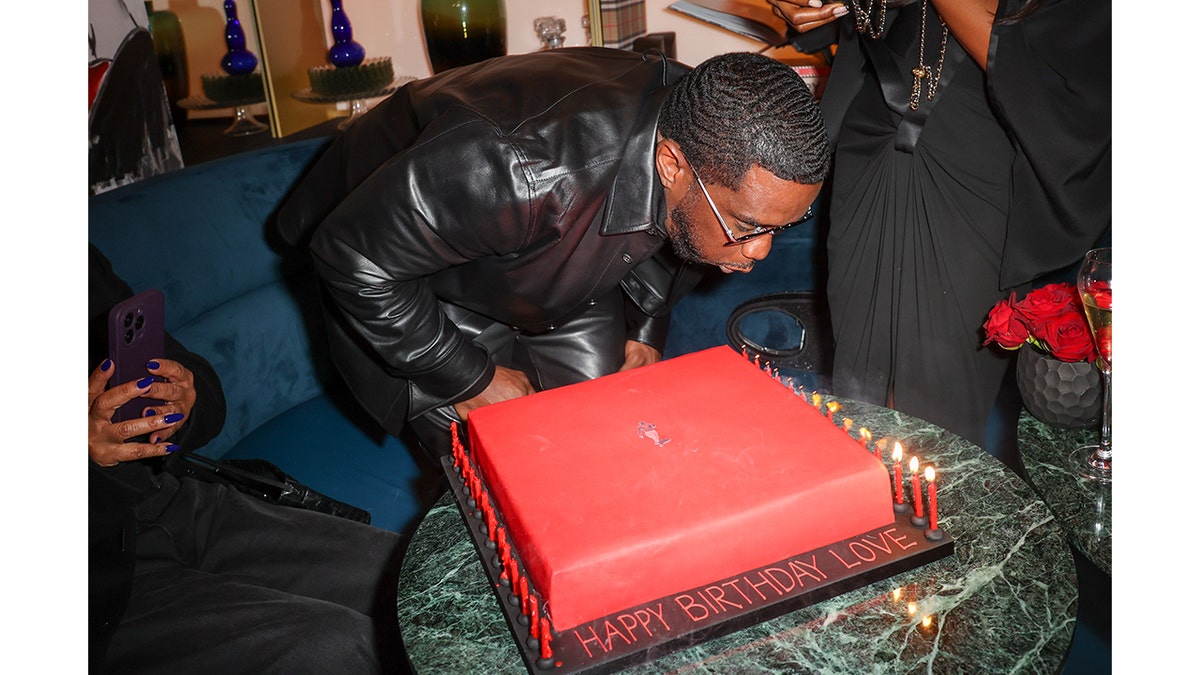 Diddy blows out candles on a red cake for his birthday in 2023