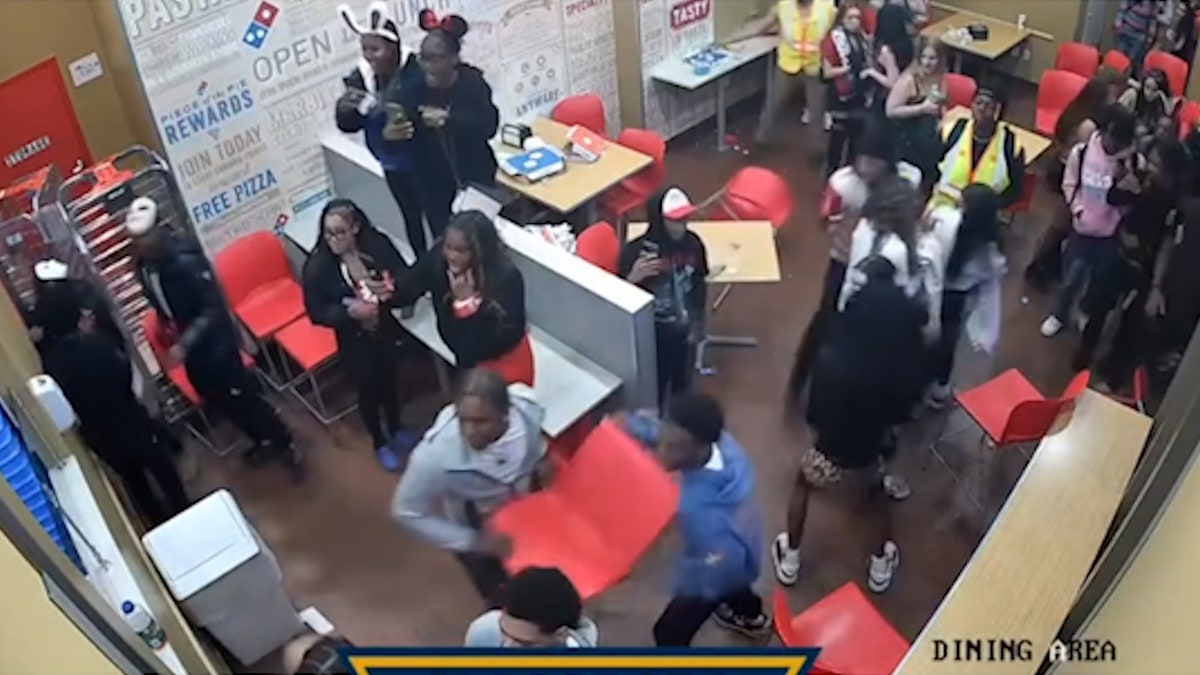 surveillance footage of two young male adults in a crowd picking up red chair