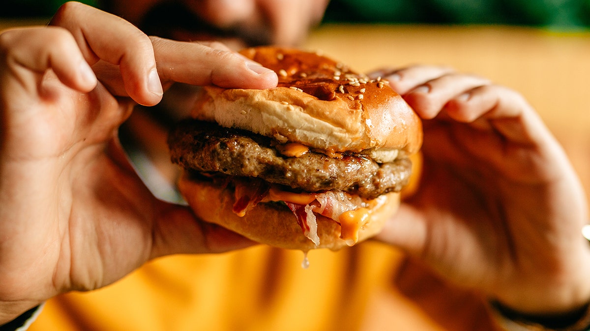 Man holding juicy cheeseburger