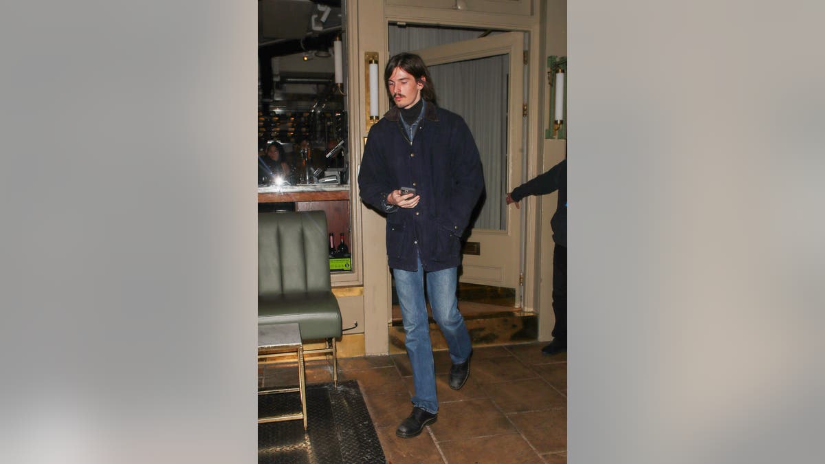 Dylan Brosnan leaves Dorian restaurant in London after a family dinner, holding his phone while walking outside.