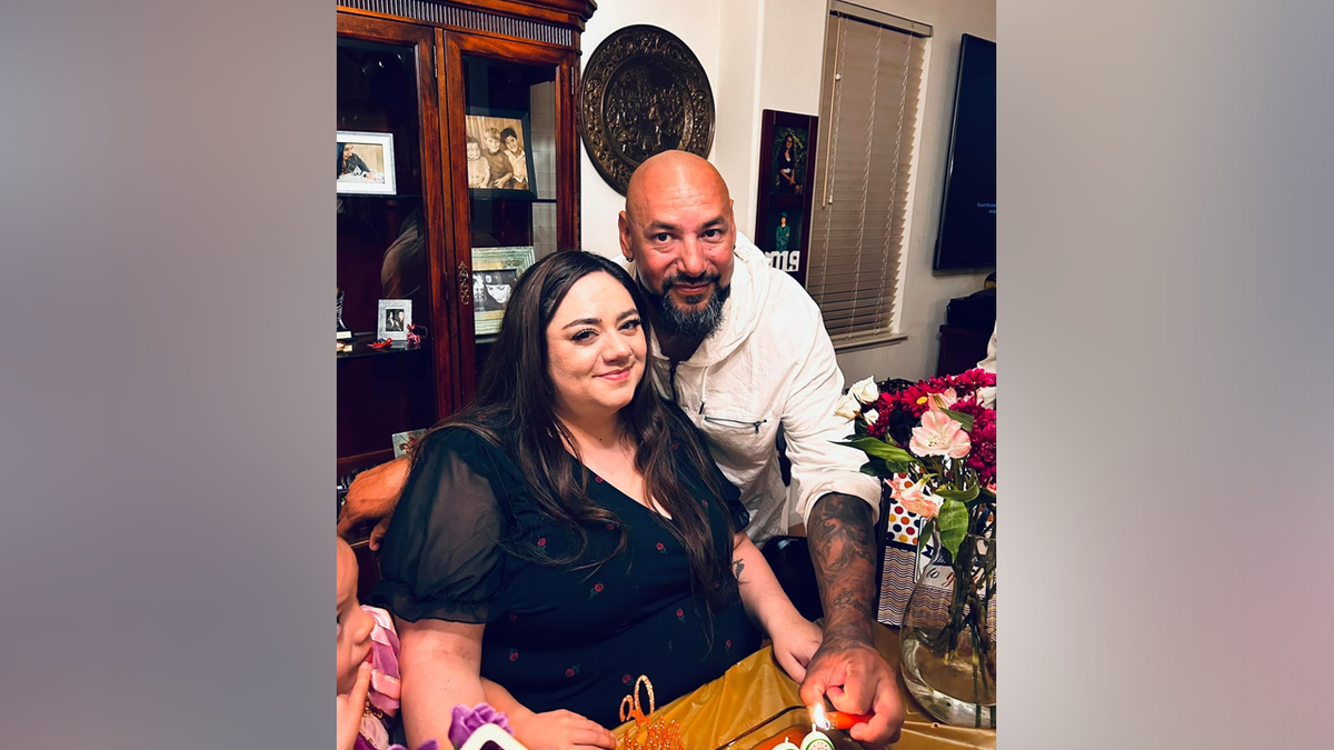 Jason Elola poses with woman and a cake