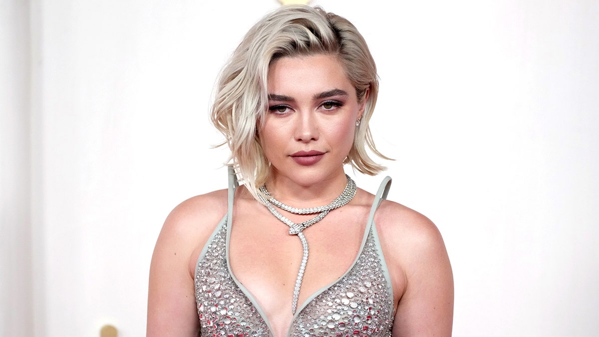 Florence Pugh poses on the red carpet at the 96th Annual Academy Awards in a silver dress.