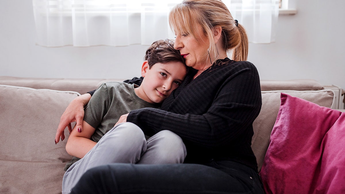 Woman keeping her young son in her arms when they are relaxing at home