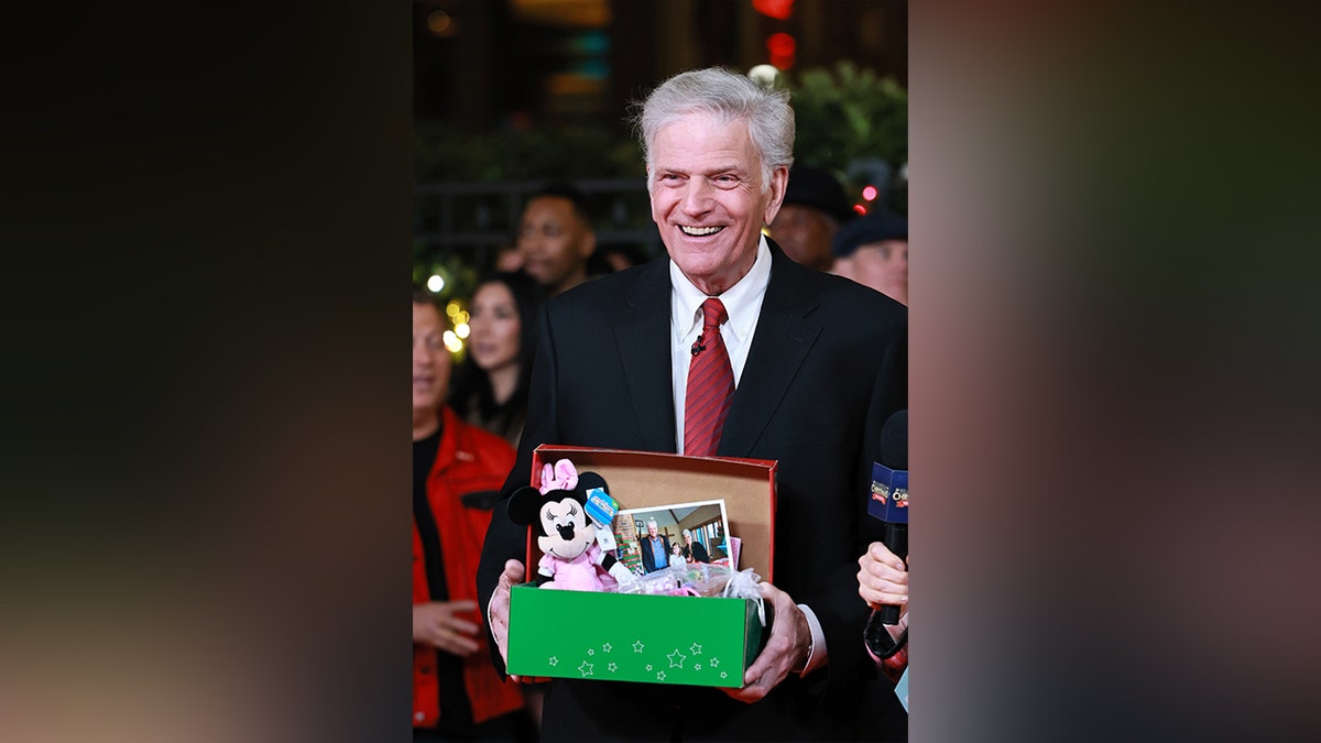 Ds. Franklin Graham poseert met een schoenendooscadeau van Operation Christmas Child