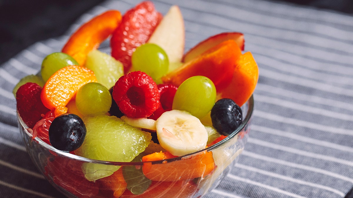 Fruit salad is displayed in a glass container.