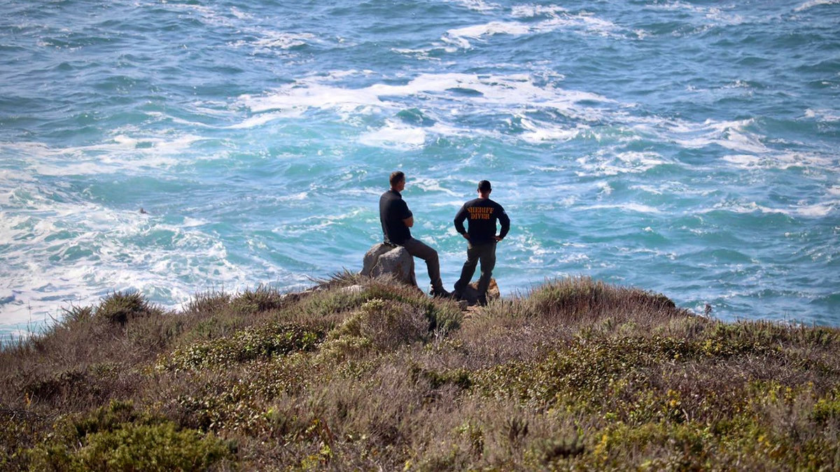 search crew members looking out into the ocean from the shoreline
