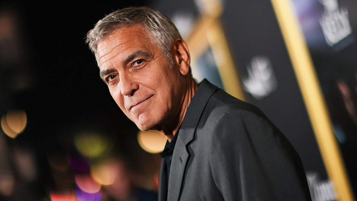 George Clooney wears grey suit on red carpet.